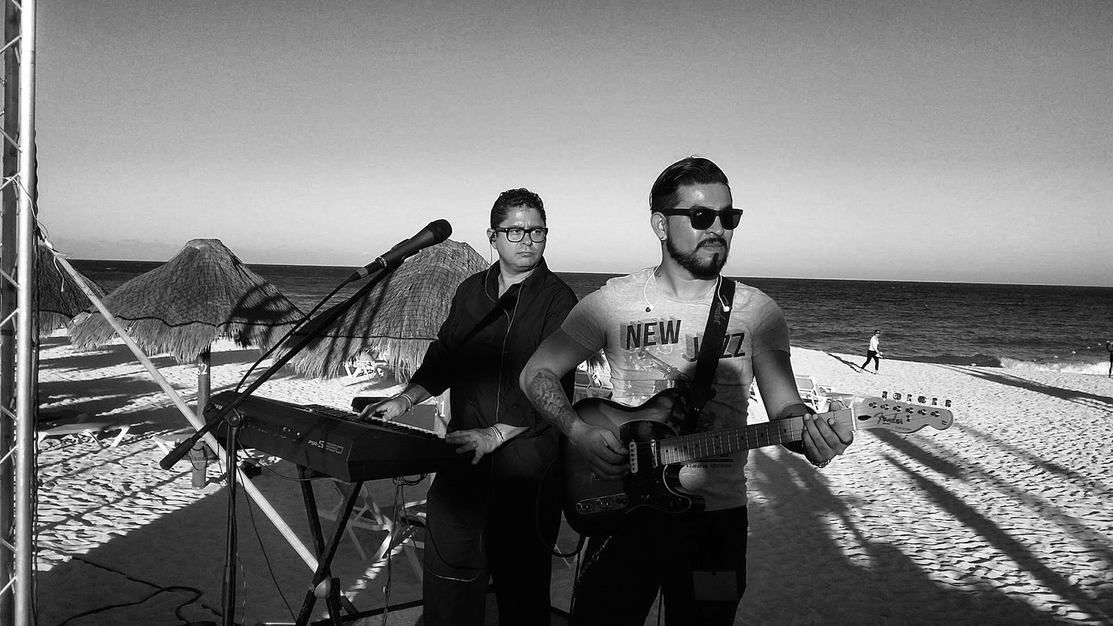 Yan al teclado junto a un guitarrista, frente al mar