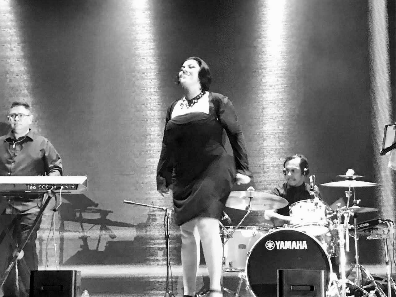 Yan al teclado en un escenario iluminado, con una cantante y batería