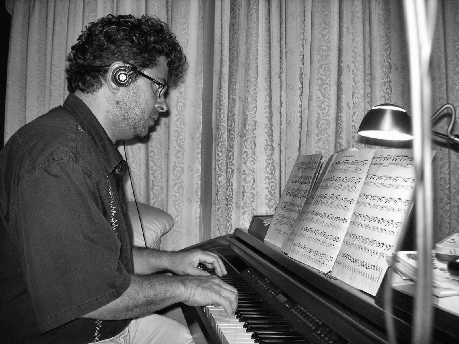 Yan Kayary con auriculares, leyendo una partitura al piano