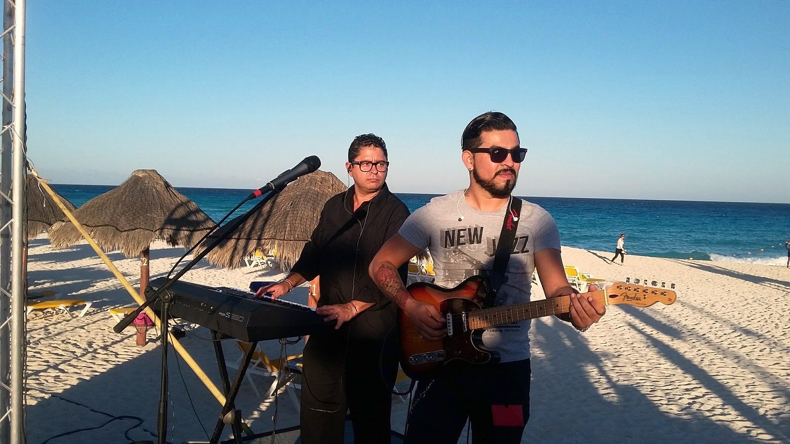Yan al teclado junto a un guitarrista, frente al mar